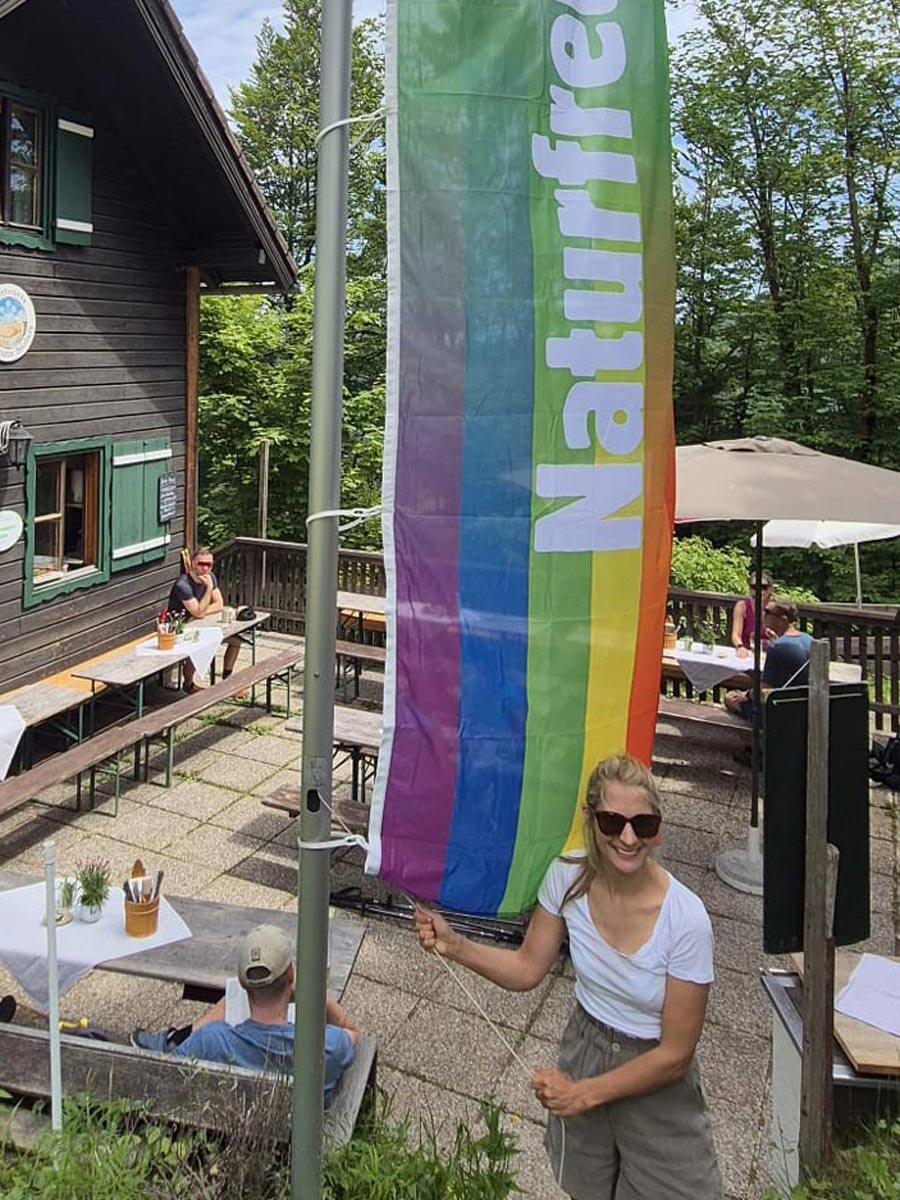 Rauchenbühelhütte Vorsitzende Sophia Burtscher auf der Rauchenbühelhütte lächelnd mit der Naturfreunde Regenbogenflagge