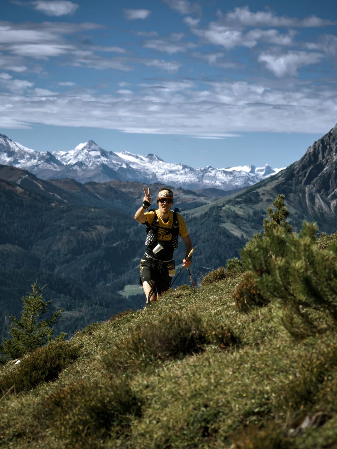 Trailrunner beim Alpin Team Trail 2026 in Werfenweng Ein Trailrunner winkt beim Alpin Team Trail 2026 in Werfenweng auf dem Bergpfad, im Hintergrund schneebedeckte Gipfel