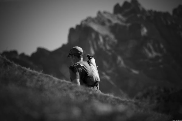 Trailrunner am Berghang schwarz-weiß Alpin Team Trail 2026 Schwarz-Weiß-Aufnahme eines Trailrunners auf einem Berghang vor Felsgipfeln beim Alpin Team Trail 2026