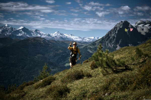 Trailrunner vor Gipfeln Alpin Team Trail 2026 Ein Trailrunner läuft beim Alpin Team Trail 2026 einen Berghang hinauf, dahinter schneebedeckte Gipfel