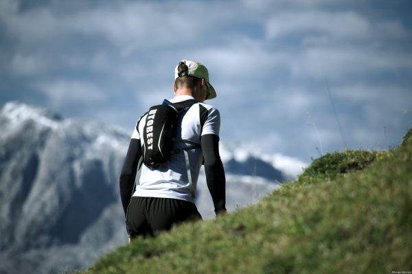 Trailrunner von hinten Alpin Team Trail 2026 Trailrunner mit Laufrucksack von hinten auf einem Berghang beim Alpin Team Trail 2026