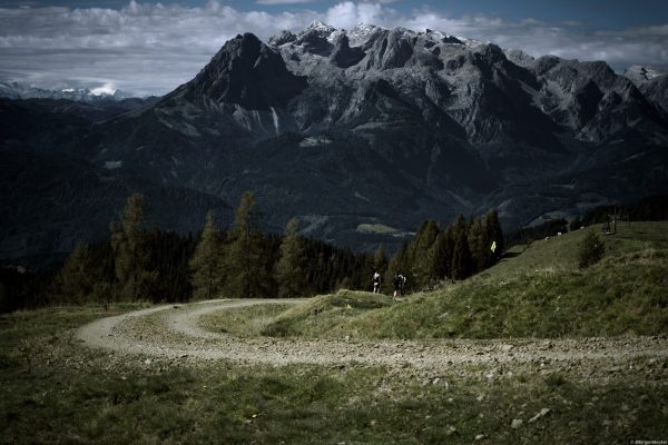 Schotterweg mit Bergmassiv Alpin Team Trail 2026 Schotterweg durch eine Almlandschaft mit Bergmassiv im Hintergrund – Strecke des Alpin Team Trail 2026 bei Werfenweng